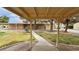 Inviting view of the property featuring a well-manicured lawn, mature trees, and a covered walkway at 3580 Unicorn Ave, Pahrump, NV 89048