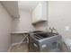 Functional laundry room with modern washer and dryer units, storage shelves, and ample space for laundry tasks at 5010 Mick Pl, Las Vegas, NV 89103