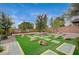 Backyard with stone accents, manicured synthetic lawn, mature landscaping, and privacy walls at 549 Via Balizan Ave, Las Vegas, NV 89123
