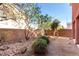 Spacious backyard featuring desert landscaping, trees, shrubs, and a brick wall at 5518 Ovando Way, Las Vegas, NV 89122