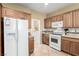 Well-lit kitchen featuring white appliances, wooden cabinets, and access to the laundry room at 5518 Ovando Way, Las Vegas, NV 89122