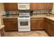 Kitchen with tile floors, tile backsplash, wooden cabinets, and white appliances at 5518 Ovando Way, Las Vegas, NV 89122