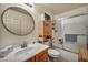 Bathroom with wood cabinet, large round mirror and bath/shower combo at 5578 River Highlands Pl, Las Vegas, NV 89122
