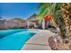 Backyard oasis featuring a sparkling pool, covered patio, and lush tropical landscaping at 5578 River Highlands Pl, Las Vegas, NV 89122