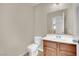 Compact bathroom with a toilet, wood vanity, and a large mirror at 5845 Killala Ct, Las Vegas, NV 89110