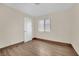 Neutral bedroom featuring wood-look flooring, a window, and a white door at 5845 Killala Ct, Las Vegas, NV 89110