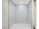 Bright white bathroom features a tub with elegant marble style tile at 609 Greenbriar Townhouse Way, Las Vegas, NV 89121