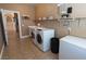 Laundry room with washer, dryer, shelves, white colored walls and accents and tan colored tile flooring at 6493 Yellow Bells Ct, Las Vegas, NV 89131
