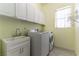 A well-equipped laundry room with a sink, washer, dryer, white cabinets and a window at 7549 Evening Falls Dr Dr, Las Vegas, NV 89131