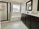 Bright bathroom with a glass-enclosed shower, large bathtub, and a double sink vanity with dark cabinets at 8532 Caddy Corner St, Las Vegas, NV 89139