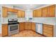 Updated kitchen featuring wooden cabinets, stainless steel appliances, modern backsplash, and tile floors at 8600 Soneto Ln, Las Vegas, NV 89117