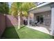 Serene backyard with artificial turf, outdoor grill, dining area, and a lush palm tree at 9277 Valley Ranch Ave, Las Vegas, NV 89178