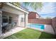 Inviting backyard featuring a small pool, covered patio with dining set, and well-maintained artificial grass at 9277 Valley Ranch Ave, Las Vegas, NV 89178
