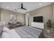 Comfortable staged bedroom with a modern ceiling fan, sleek white dresser and hardwood floors at 19 Hilltop Crest St, Henderson, NV 89011