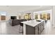 Open-concept living room featuring a gray sectional, kitchen island with seating, and a dining area at 31 Autumn Palm Ave, Henderson, NV 89011