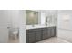 Bathroom with double vanity, gray cabinets, tiled flooring, toilet, and mirror reflecting a glass shower at 352 Tigullio Ave, Henderson, NV 89011