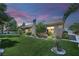 Dusk view of the backyard featuring a lush lawn, mature landscaping, and a charming single-story home at 4722 Blue Mesa Way, Las Vegas, NV 89129