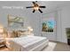 Stylish bedroom featuring a ceiling fan and a window overlooking palm trees at 4722 Blue Mesa Way, Las Vegas, NV 89129