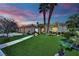 Well-manicured front yard featuring lush grass, mature trees, and a beautiful single-story home at dusk at 4722 Blue Mesa Way, Las Vegas, NV 89129