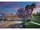 Single-story home features a three-car garage, desert landscaping, mature shade trees, and well-maintained lawn at 4722 Blue Mesa Way, Las Vegas, NV 89129