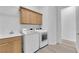 Laundry room with wood cabinets, sink, white washer and dryer, and flooring at 4722 Blue Mesa Way, Las Vegas, NV 89129