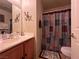 Bright bathroom with a cherry wood vanity, patterned shower curtain, and tile floor at 6080 Golden Corral Trl # 103, Henderson, NV 89011