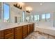 Bright bathroom with double sinks, wood cabinets, soaking tub and natural lighting at 8447 Amherst Valley St, Las Vegas, NV 89123