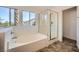 Bright bathroom featuring a soaking tub, glass enclosed shower, and tile flooring at 8447 Amherst Valley St, Las Vegas, NV 89123