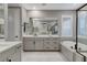 This bathroom features a double vanity with a large mirror, a bathtub and lots of natural light at 12439 Iron Bluff Ave, Las Vegas, NV 89138