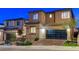 Modern two-story home at dusk, featuring a brick facade and a contemporary glass garage door at 12439 Iron Bluff Ave, Las Vegas, NV 89138