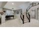 Bright foyer featuring a curved staircase, a black piano, light-colored tile flooring, and modern light fixture at 12439 Iron Bluff Ave, Las Vegas, NV 89138
