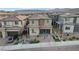 Charming two-story home with a well-manicured front yard, brick driveway, and a modern glass garage door at 12439 Iron Bluff Ave, Las Vegas, NV 89138