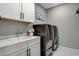 Modern laundry room featuring sleek cabinets, a utility sink, and high-end washer and dryer units at 12439 Iron Bluff Ave, Las Vegas, NV 89138
