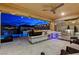 Elegant outdoor kitchen featuring a grill, sink, and refrigerator, illuminated by string lights and overlooking the pool at 12439 Iron Bluff Ave, Las Vegas, NV 89138