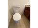 Close-up of white toilet on light wood-look flooring next to brown cabinets at 4421 Alexis Dr # 429, Las Vegas, NV 89103