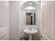 Clean bathroom with pedestal sink, arched mirror, and white textured walls at 10235 Headrick Dr, Las Vegas, NV 89166
