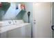 Bright laundry room with side-by-side washer and dryer, shelving, and access door at 10235 Headrick Dr, Las Vegas, NV 89166