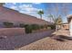 Backyard showcasing a desert landscape design with rock ground cover and mature shrubs along the high block wall at 1047 Amber Gate St, Henderson, NV 89002