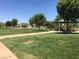A park featuring lush green grass, mature trees, a shaded picnic area, and walking paths at 1047 Amber Gate St, Henderson, NV 89002