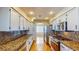 Galley kitchen boasts granite counters, white cabinets, stainless appliances, and hardwood flooring at 1532 Ascension Cir, North Las Vegas, NV 89031