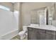 Bright bathroom with white tiling, a shower-tub combo, and vanity with gray cabinets at 1536 Unison Way # 102, Las Vegas, NV 89135