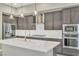 Modern kitchen featuring gray cabinetry, stainless steel appliances, and a large center island with a white countertop at 1536 Unison Way # 102, Las Vegas, NV 89135