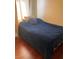Bedroom features a single bed with a blue blanket, wood floors, and natural light at 1800 Edmond St # 213, Las Vegas, NV 89146