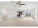 Open-concept living area with neutral carpet, bright lighting, and an adjacent kitchen at 2677 Saddle Bronze Ct, North Las Vegas, NV 89086
