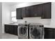 Modern laundry room with front loading washer and dryer, dark cabinets and white countertop at 29 Owl Ridge Ct, Las Vegas, NV 89135