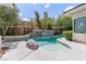 Gorgeous swimming pool with a spa and rock waterfall feature, surrounded by lush landscaping and trees in the backyard at 29 Owl Ridge Ct, Las Vegas, NV 89135