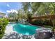 Inviting backyard pool and spa with a rock waterfall feature, surrounded by lush greenery and mature trees at 29 Owl Ridge Ct, Las Vegas, NV 89135