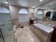 Bright bathroom featuring a soaking tub, vanity with vessel sink, and a window with decorative glass at 2913 Domino Way, Las Vegas, NV 89117