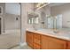 Bathroom with a double sink vanity with oak cabinets and a glimpse of the shower at 3071 Misty Moon Ave, Henderson, NV 89052
