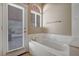 Bright bathroom with a large soaking tub next to a window and a door to the patio at 3071 Misty Moon Ave, Henderson, NV 89052